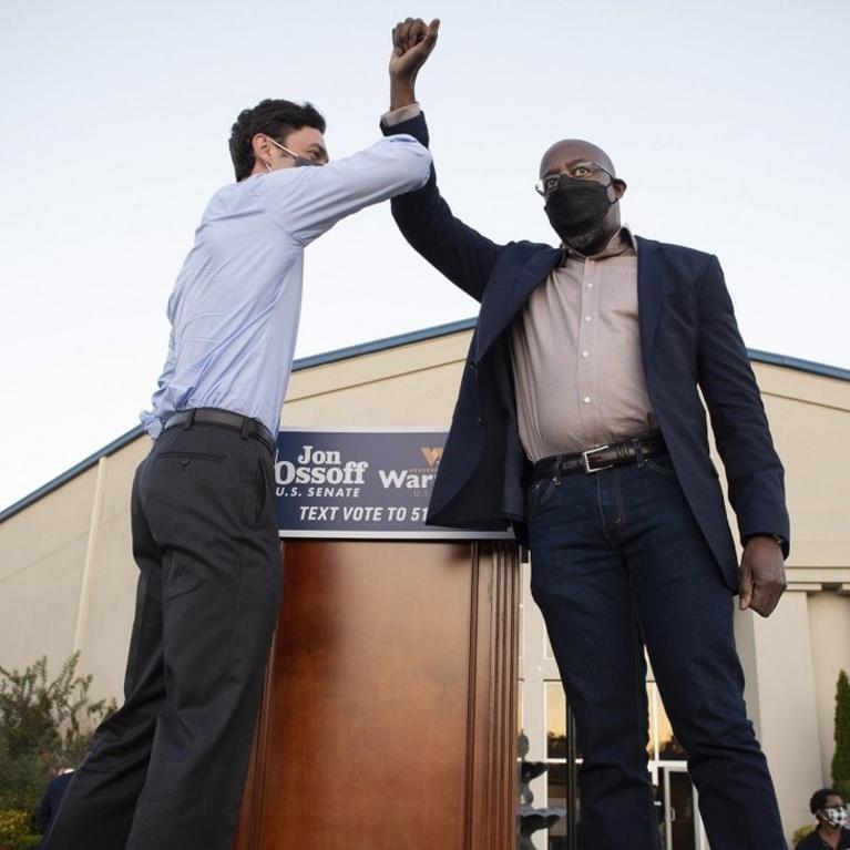 Democratic candidates Jon Ossoff, left, and Raphael Warnock bump elbows on stage at a rally in Jonesboro, Georgia on November 19. Photo: Zuma Press via TNS