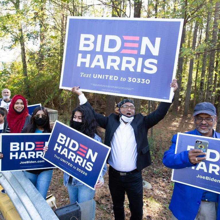 Voters wave Biden-Harris campaign signs at the entrance to a polling station in Gwinnett County, Ga., on Nov 3., 2020. | Jessica McGowan/Getty Images