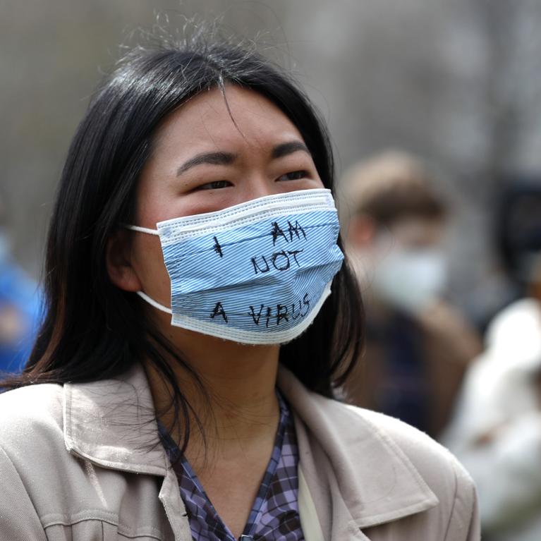 A demonstrator wearing a mask saying "I am not a virus" listens to a speech at a rally against Asian hate crimes, Saturday, March 27, 2021 at Chicago's Grant Park. The gathered crowd demanded justice for the victims of the Atlanta spa shooting and for an end to racism, xenophobia and misogyny. (AP Photo/Shafkat Anowar)