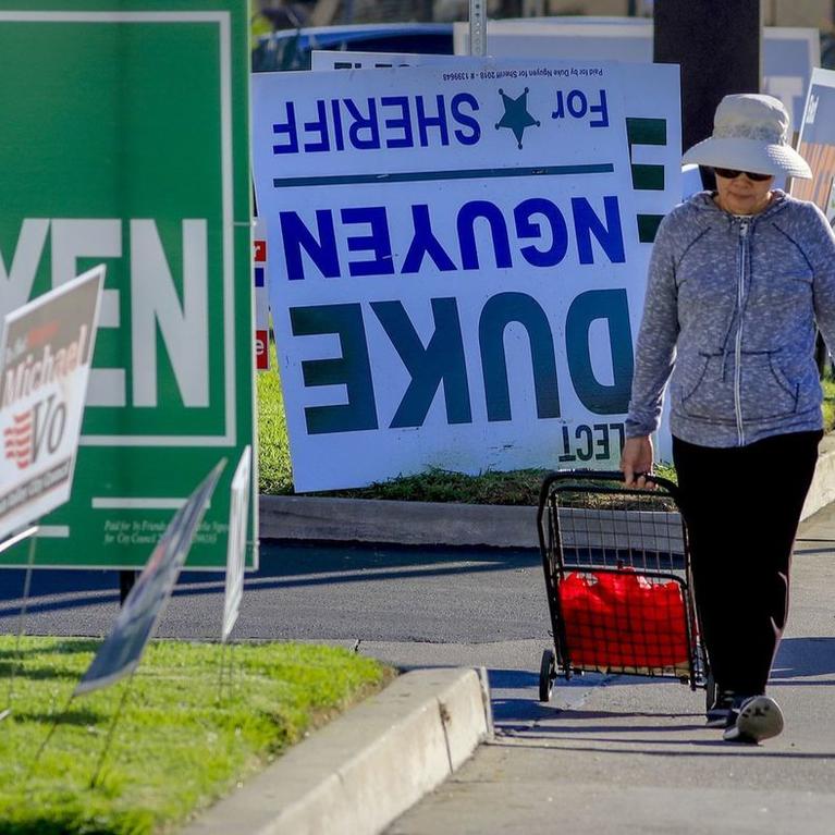 Pedestrians walk past a row of political signs and posters along Bolsa Avenue in Westminster. In Orange County, 24 people of Vietnamese descent are running for public office. (Mark Boster / For The Times)