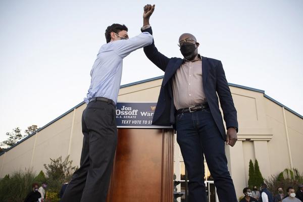 Democratic candidates Jon Ossoff, left, and Raphael Warnock bump elbows on stage at a rally in Jonesboro, Georgia on November 19. Photo: Zuma Press via TNS