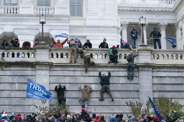 A violent mob scales Capitol walls on Wednesday. Business recognizes that this isn’t a good look for the economy of a major democracy, and they’re blaming President Trump.(Jose Luis Magana / Associated Press)