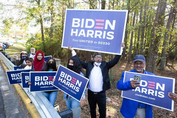 Voters wave Biden-Harris campaign signs at the entrance to a polling station in Gwinnett County, Ga., on Nov 3., 2020. | Jessica McGowan/Getty Images