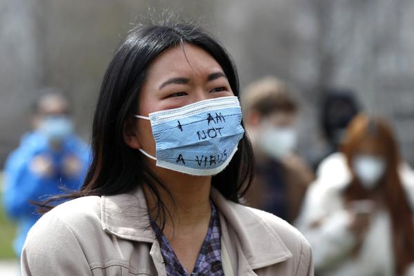 A demonstrator wearing a mask saying "I am not a virus" listens to a speech at a rally against Asian hate crimes, Saturday, March 27, 2021 at Chicago's Grant Park. The gathered crowd demanded justice for the victims of the Atlanta spa shooting and for an end to racism, xenophobia and misogyny. (AP Photo/Shafkat Anowar)