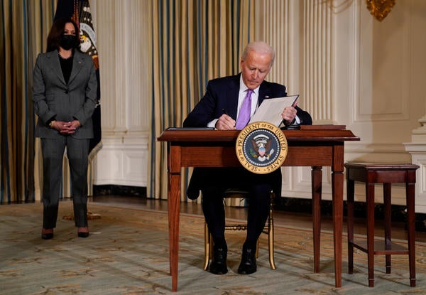 President Joe Biden signs executive orders on racial equity in the State Dining Room of the White House, Tuesday, Jan. 26, 2021, in Washington. Vice President Kamala Harris listens at left. (AP Photo/Evan Vucci)