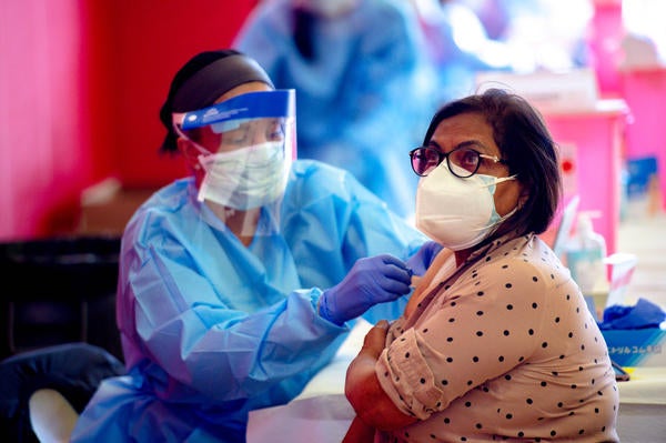 Farida Uddin, a 65-year-old Corona resident, receives a dose of the Moderna COVID-19 vaccine inside the Corona High School gymnasium Thursday, Jan. 14, 2021, as shots expand to those 65 and older in Riverside County. (Photo by Watchara Phomicinda, The Press-Enterprise/SCNG)