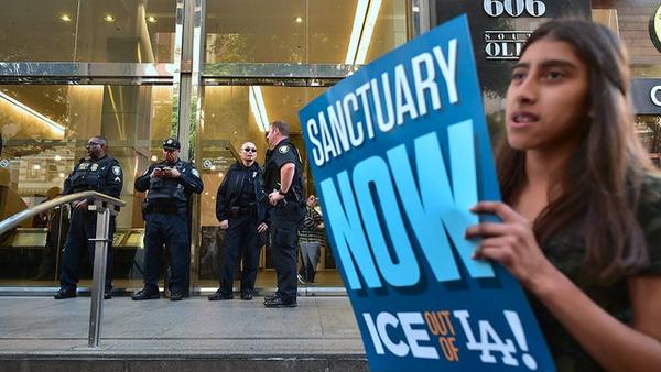 Image of a protestor in Los Angeles fighting for sanctuary city status in front of a government building and security officials