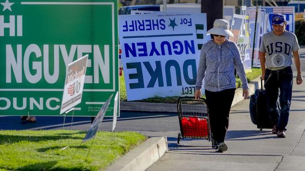 Pedestrians walk past a row of political signs and posters along Bolsa Avenue in Westminster. In Orange County, 24 people of Vietnamese descent are running for public office. (Mark Boster / For The Times)